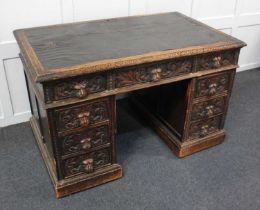 A Flemish style carved oak pedestal desk the rectangular leather inset top above an arrangement of