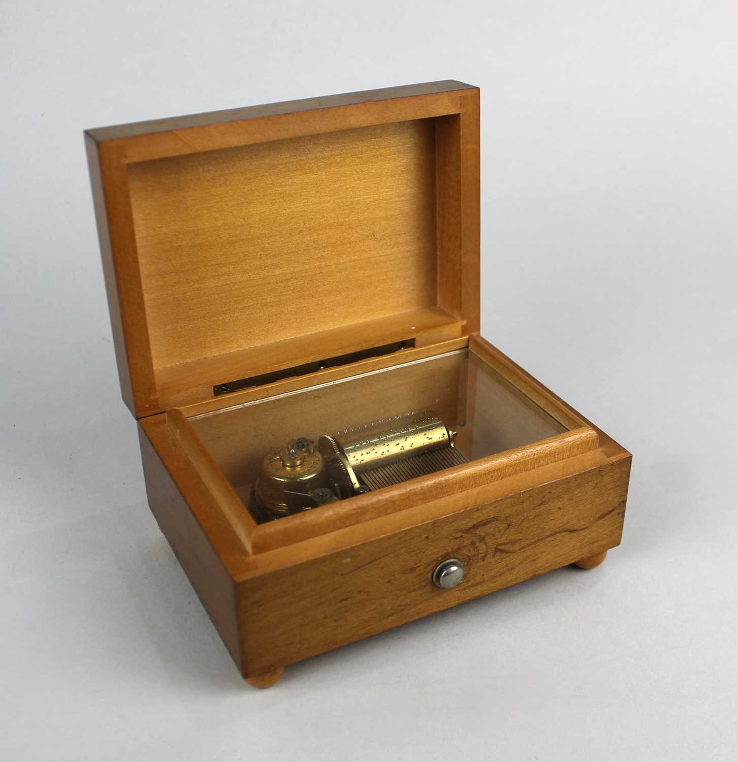 A Swiss small music box in plain rectangular wooden case with slide button switch, label beneath '