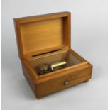 A Swiss small music box in plain rectangular wooden case with slide button switch, label beneath '