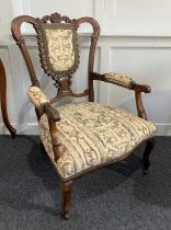A Victorian armchair open framed back with upholstered panel and padded arms, on cabriole legs and