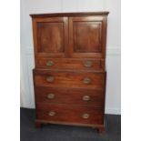 A George III mahogany cabinet on chest the top section with two panelled cupboard doors and drawer