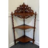 A Victorian rosewood three-tier corner whatnot with pierced surmount on spiral turned supports,