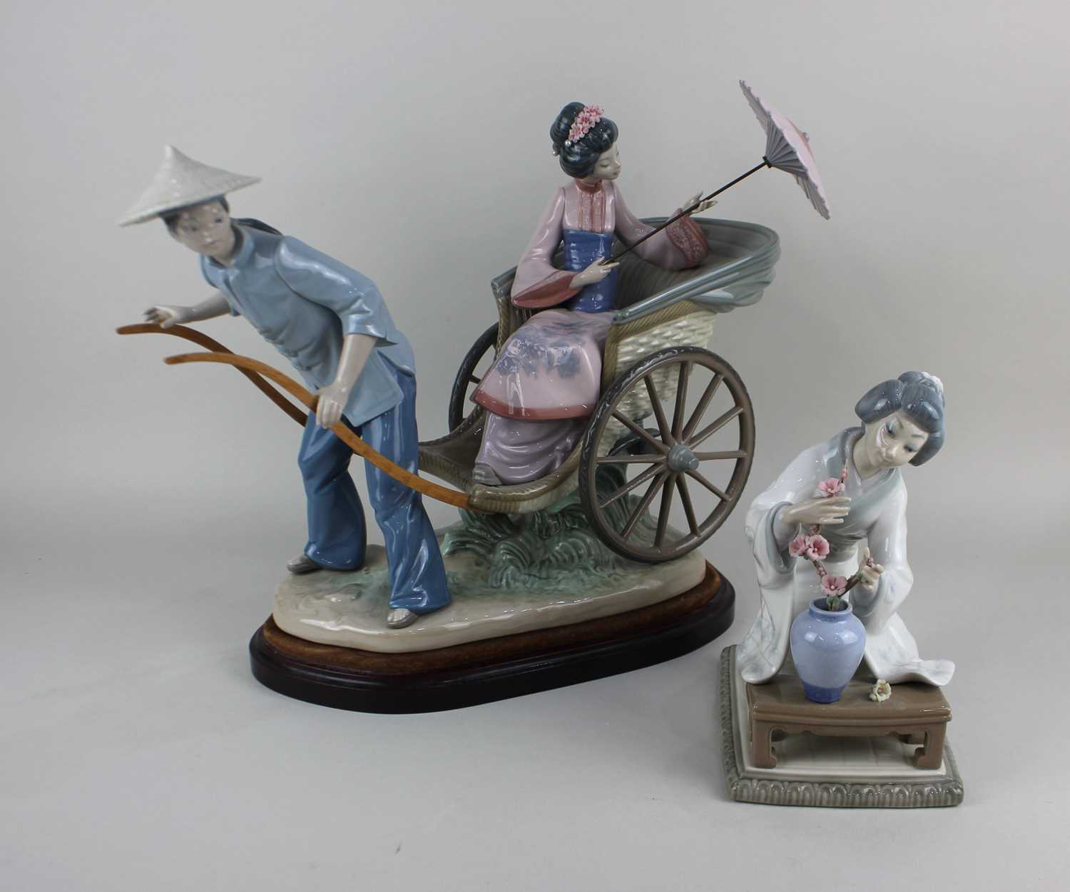 A Lladro porcelain figure group of a geisha with parasol riding a rickshaw, approx 32cm high, on