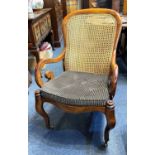A 19th Century mahogany framed caned bergere armchair, with scrolled open arms, serpentine front,