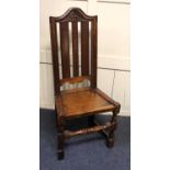 An 18th century oak hall chair, with fleur de lis carved arched top rail, dished seat, turned and