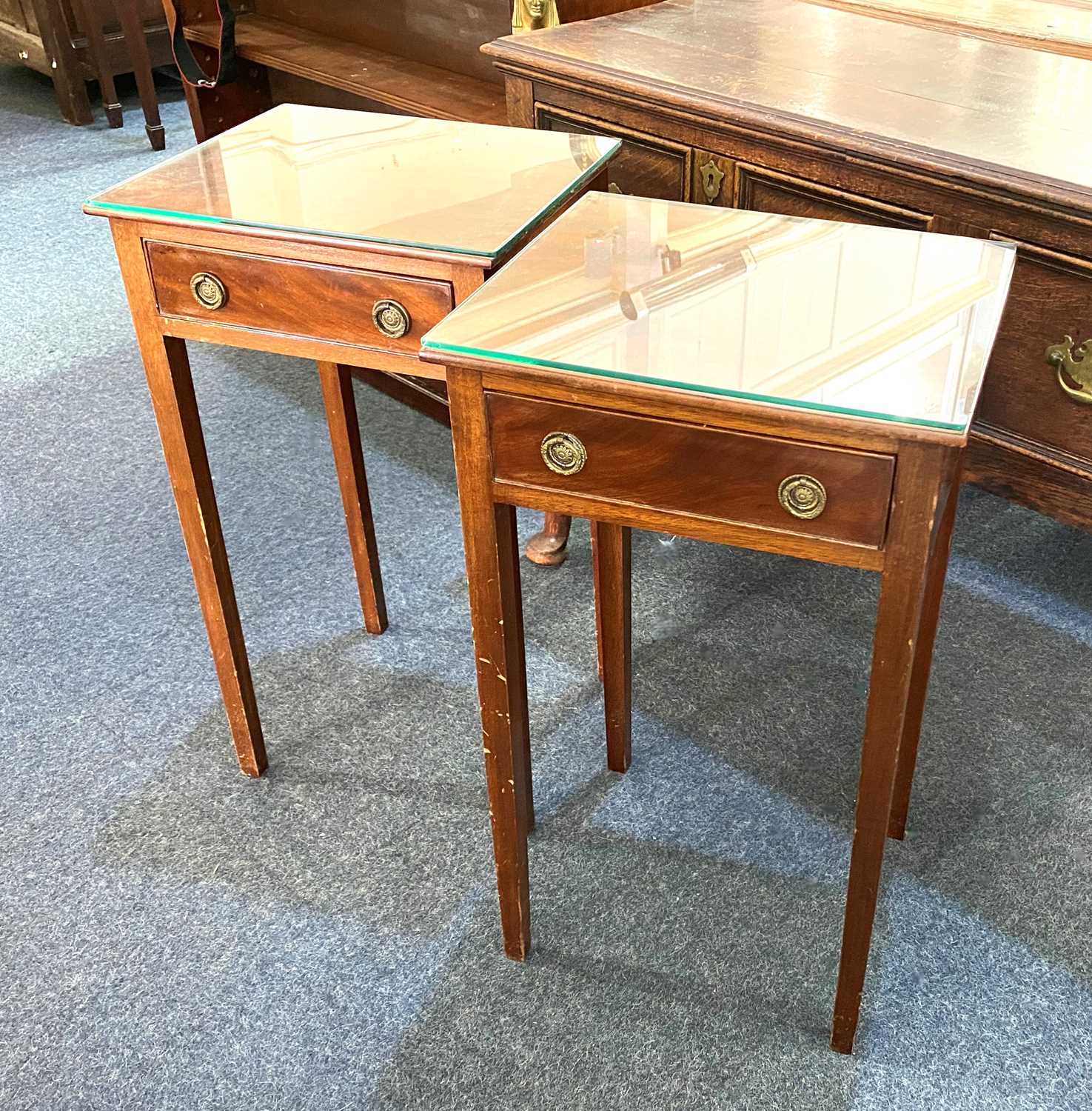 A pair of mahogany bedside tables with square tops and single drawer with drop ring handles, on