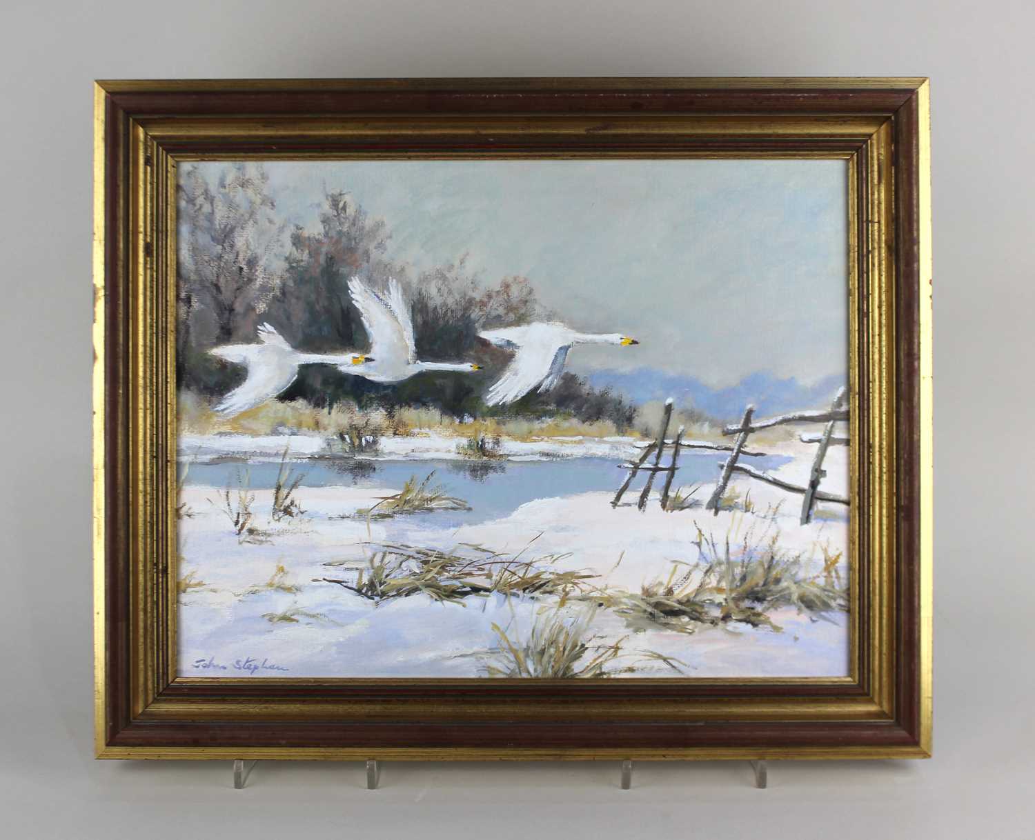 John Stephen (b 1926), snow covered landscape with swans in flight 'Winter Marshes', oil on board,