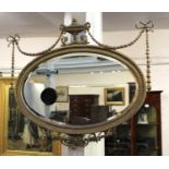 A 19th century gilt and gesso wall mirror with oval mirror plate surmounted by urn and ribbon tied