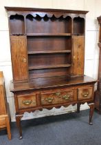 An early 19th century and later oak dresser the later top section with panel back, three shelves and
