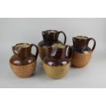 Four Doulton Lambeth glazed stoneware jugs decorated in light relief with harvest scenes tallest