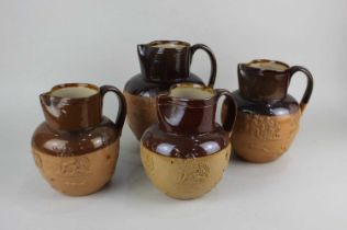 Four Doulton Lambeth glazed stoneware jugs decorated in light relief with harvest scenes tallest