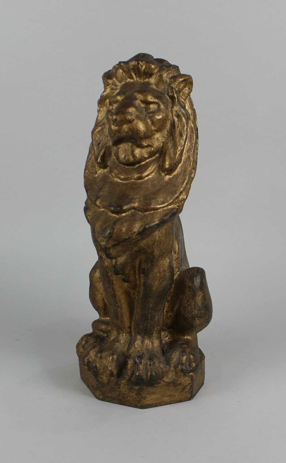 A heavy gold painted metal doorstop in the form of a seated lion 33cm high