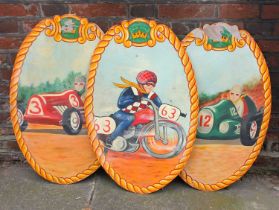 Three painted oval wooden signs possibly from a fairground, decorated with figures in racing cars