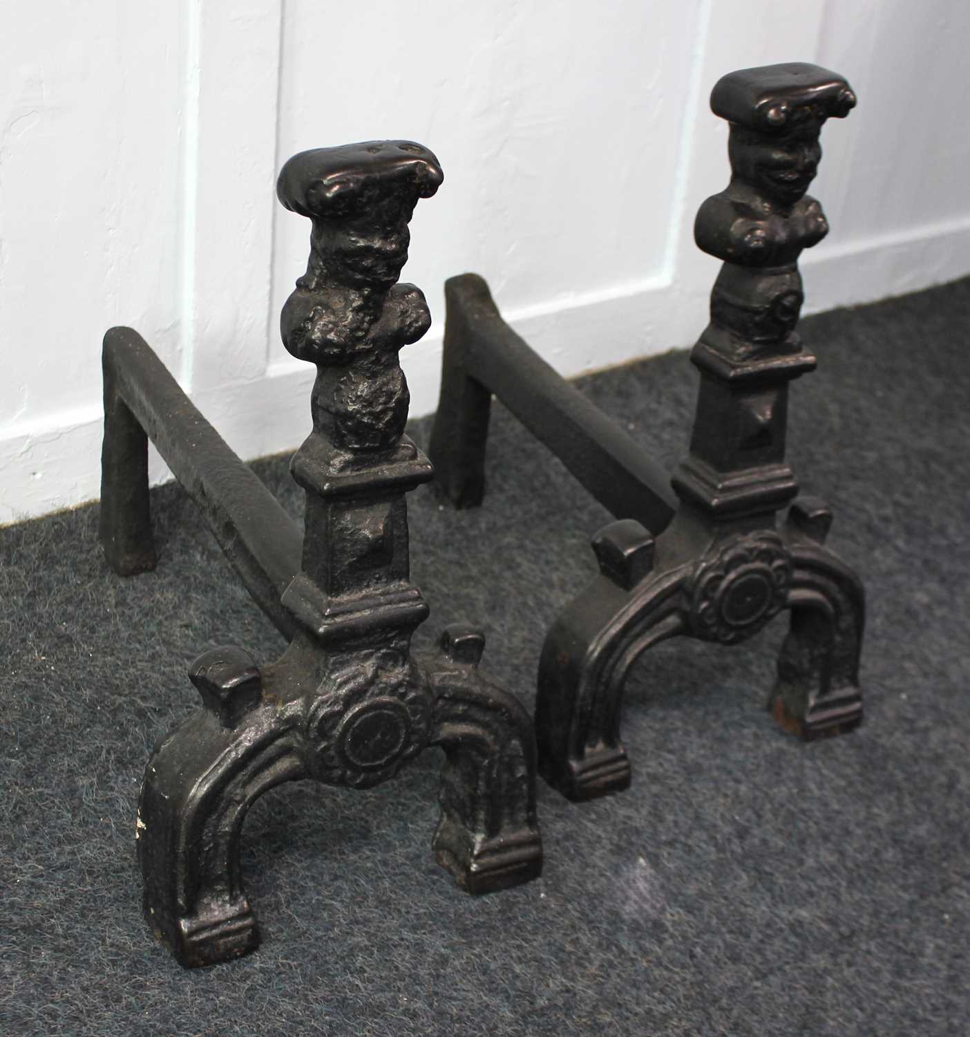 A pair of cast iron fire dogs in the form of busts on plinths, 47cm