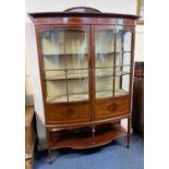 An Edwardian mahogany bowfront display cabinet with two glazed panel doors enclosing two shelves,