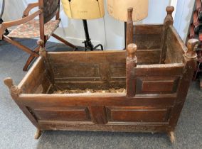 An 18th century wooden cradle with panelled sides and turned corner finials, on rocker supports,