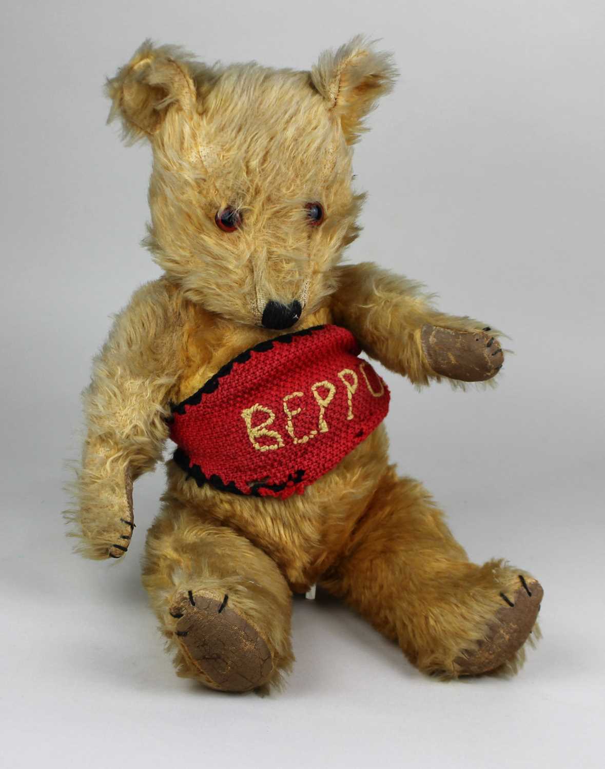 A vintage teddy bear, with golden plush, glass eyes, hand stitched nose, jointed limbs, 44cm high.