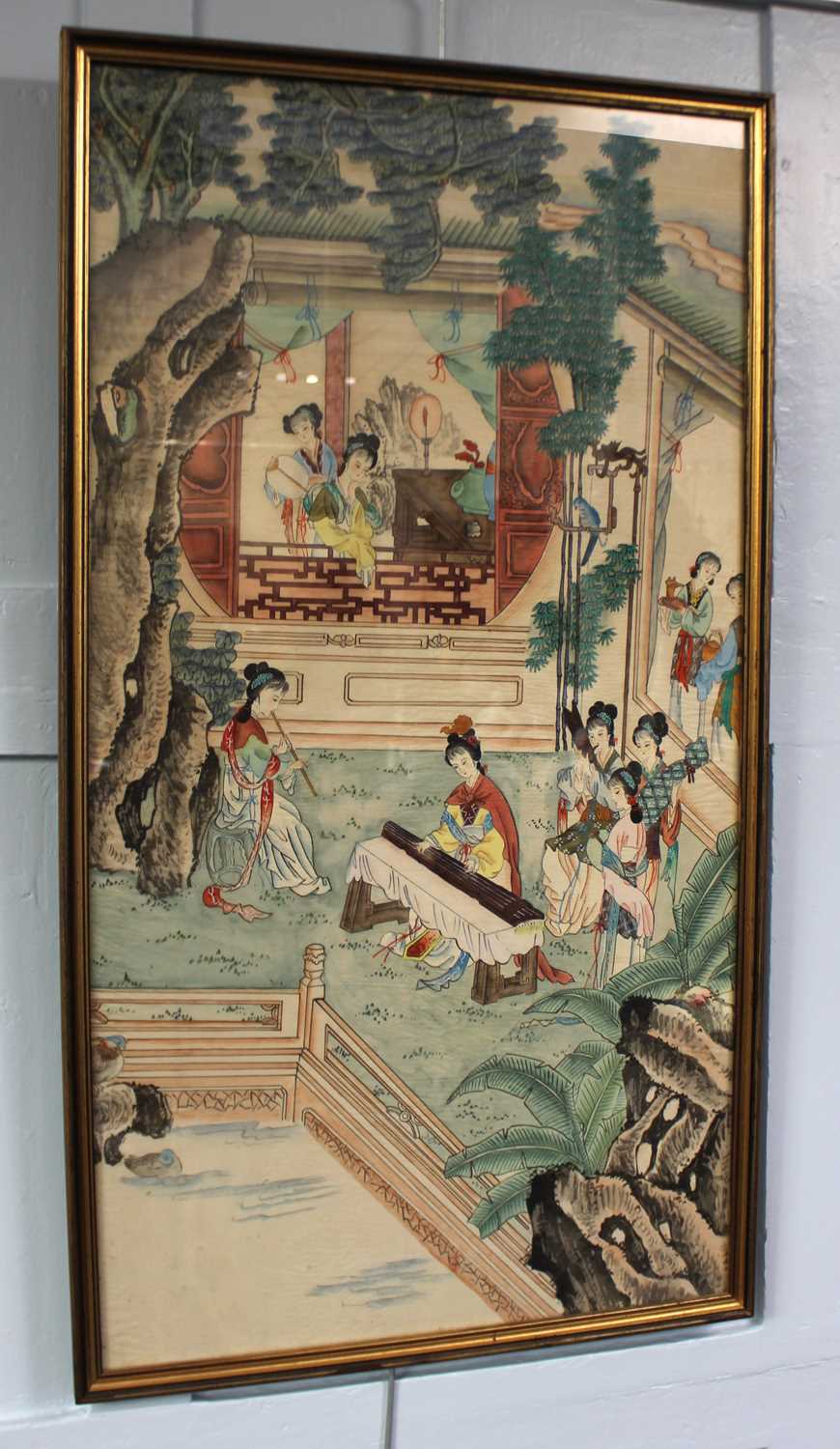 A framed Chinese painting on rice paper of figures engaged in various pursuits in a garden setting