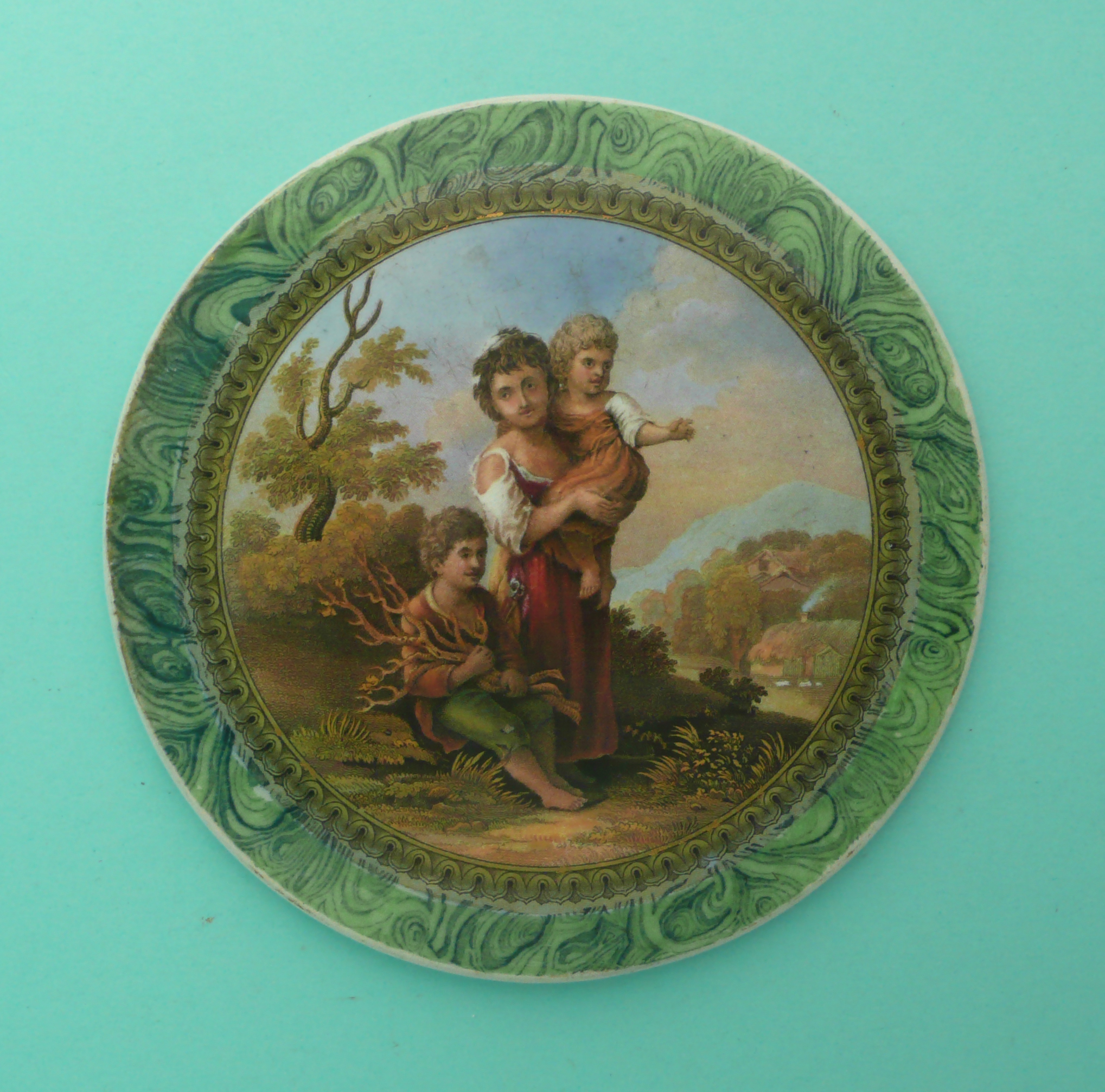 A circular malachite ground plaque: The Cottage Children (313). (potlid, pot lid, Prattware,