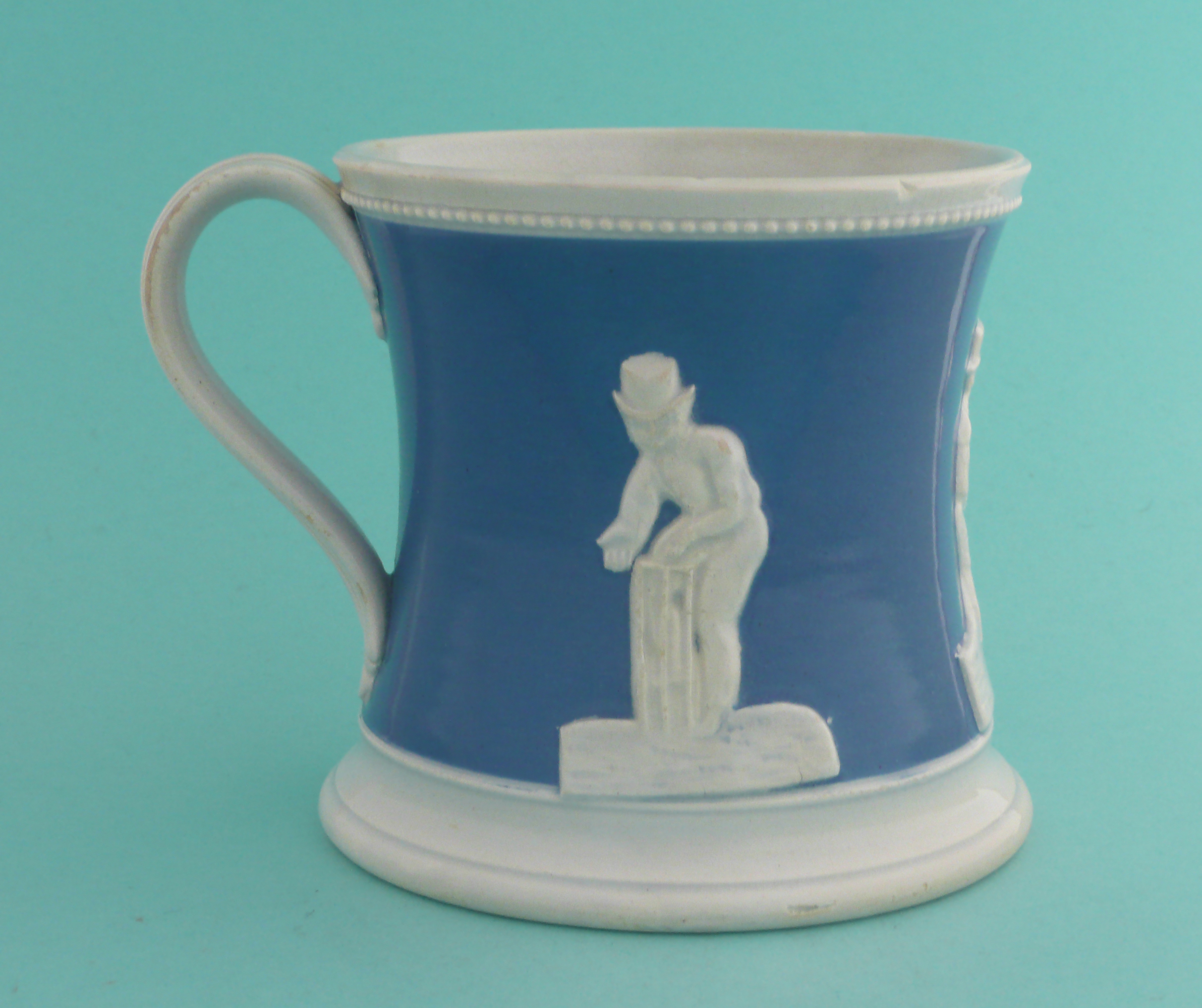 Cricket: a pottery mug the waisted body coloured blue and moulded in white with figures, circa 1850, - Image 2 of 5