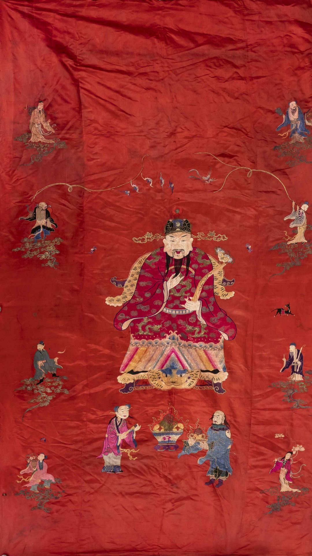 Red silk cloth, China, embroidered with numerous figures and officials on a tiger skin throne,
