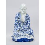 Blue and white figure, China 20th century, meditating monk with wrinkled robe and bats between bands