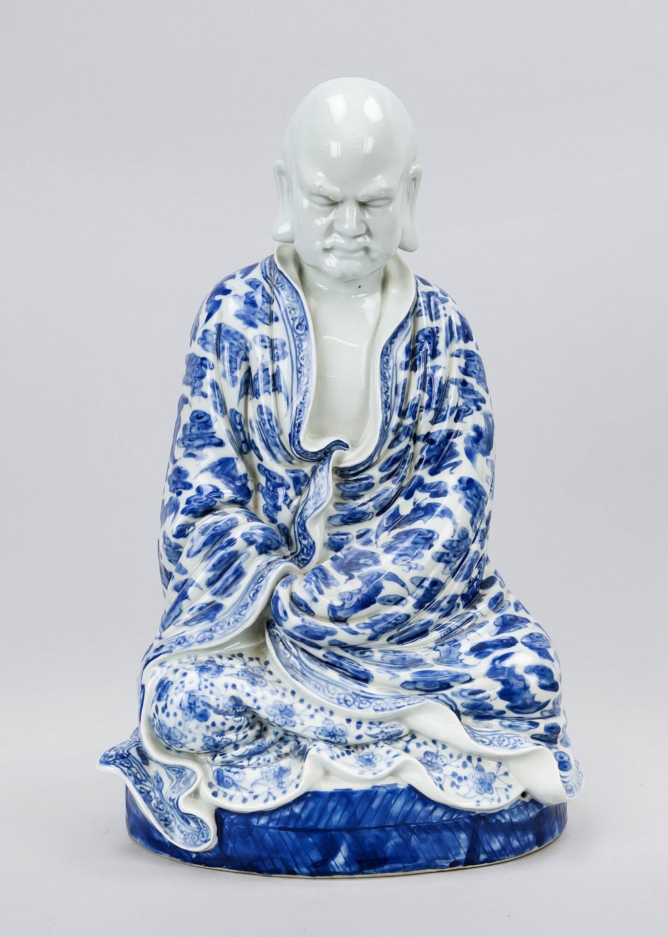 Blue and white figure, China 20th century, meditating monk with wrinkled robe and bats between bands