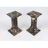 A pair of reeded flower columns, 20th century, polished black stone with natural polychrome pattern,