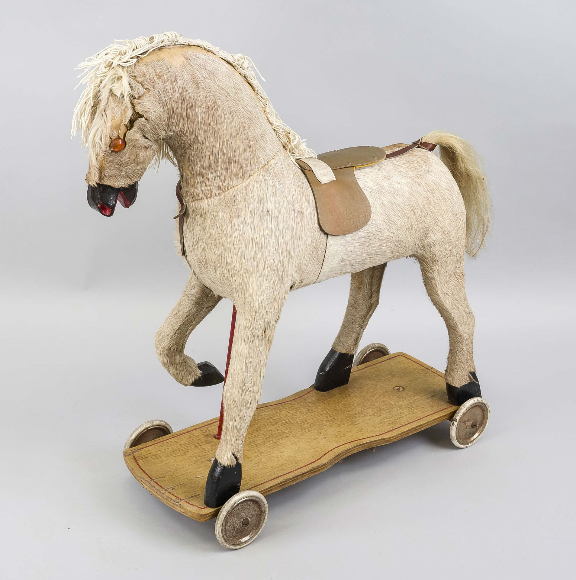 Riding horse for children, c. 1900, placed in a walking position on a wooden plinth with castors,
