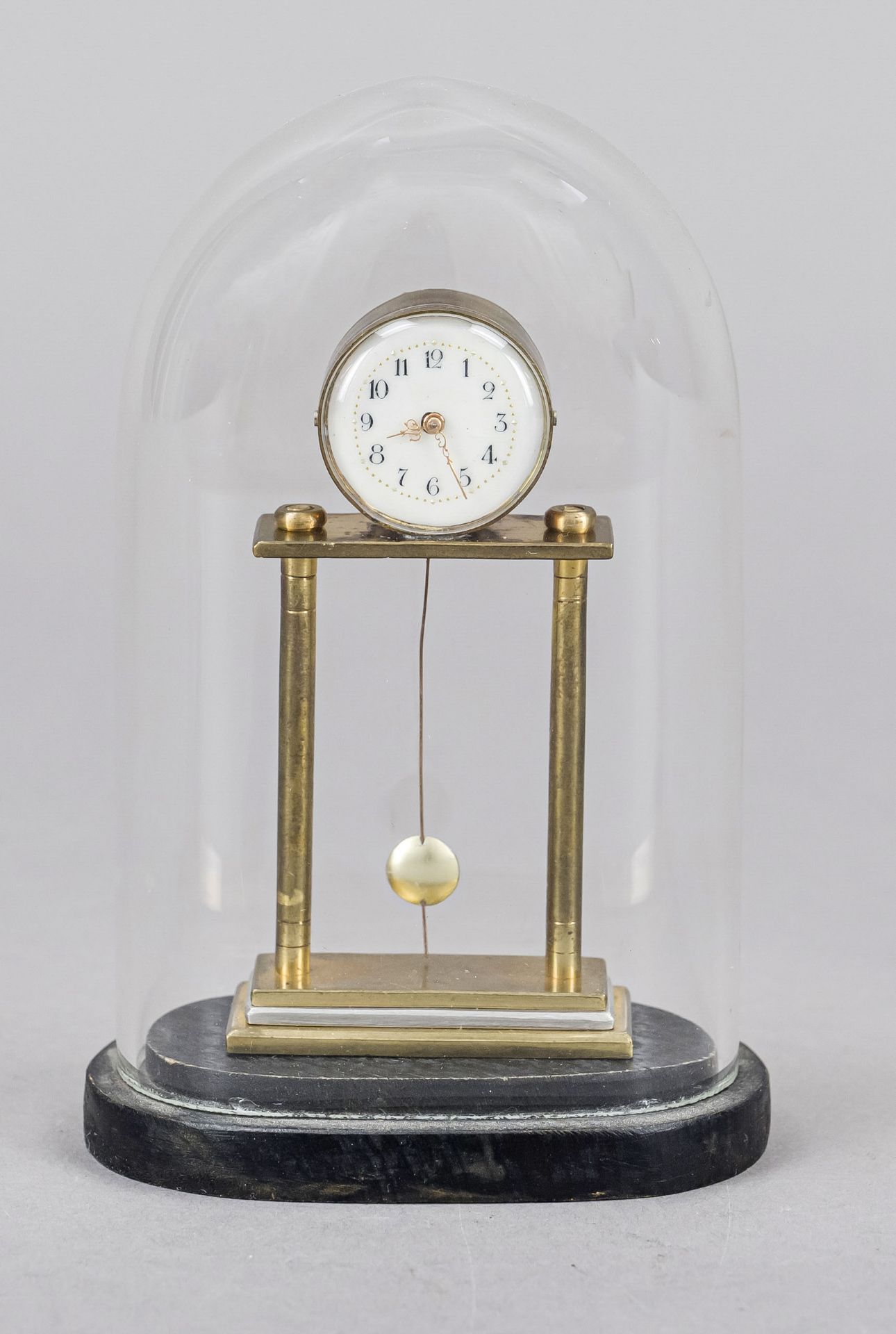 Miniature portal clock, brass, under oval glass dome on ebonized base, 20th century, white enamel