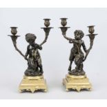 A pair of figural candlesticks, France 19th century, patinated bronze, gilded on a square stand,