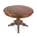 Round dining table, 19th century, mahogany, opulently carved base with four volute feet, h. 76 cm,