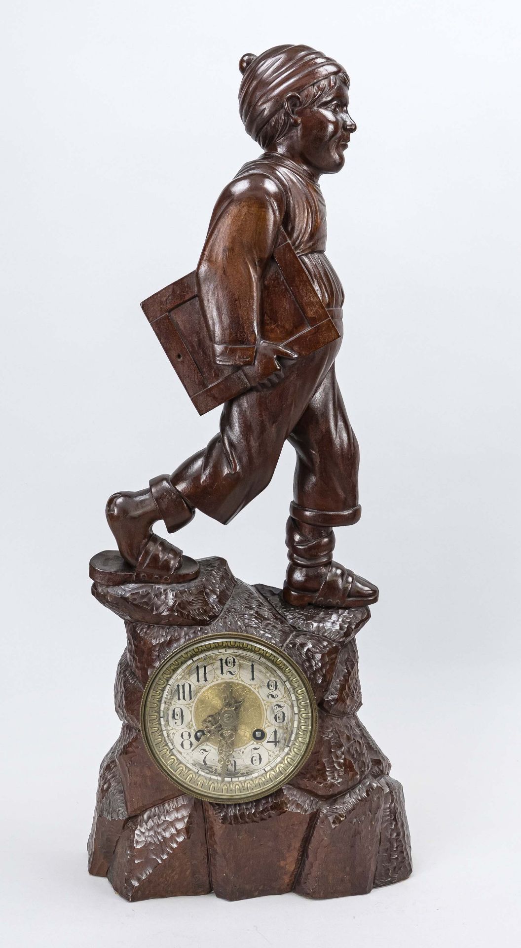 Large carved figure of a boy with writing tablet, mahogany, around 1900, the clock in a carved base,