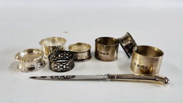 A GROUP OF 7 ASSORTED SILVER NAPKIN RINGS ALONG WITH A SILVER HANDLED LETTER OPENER.