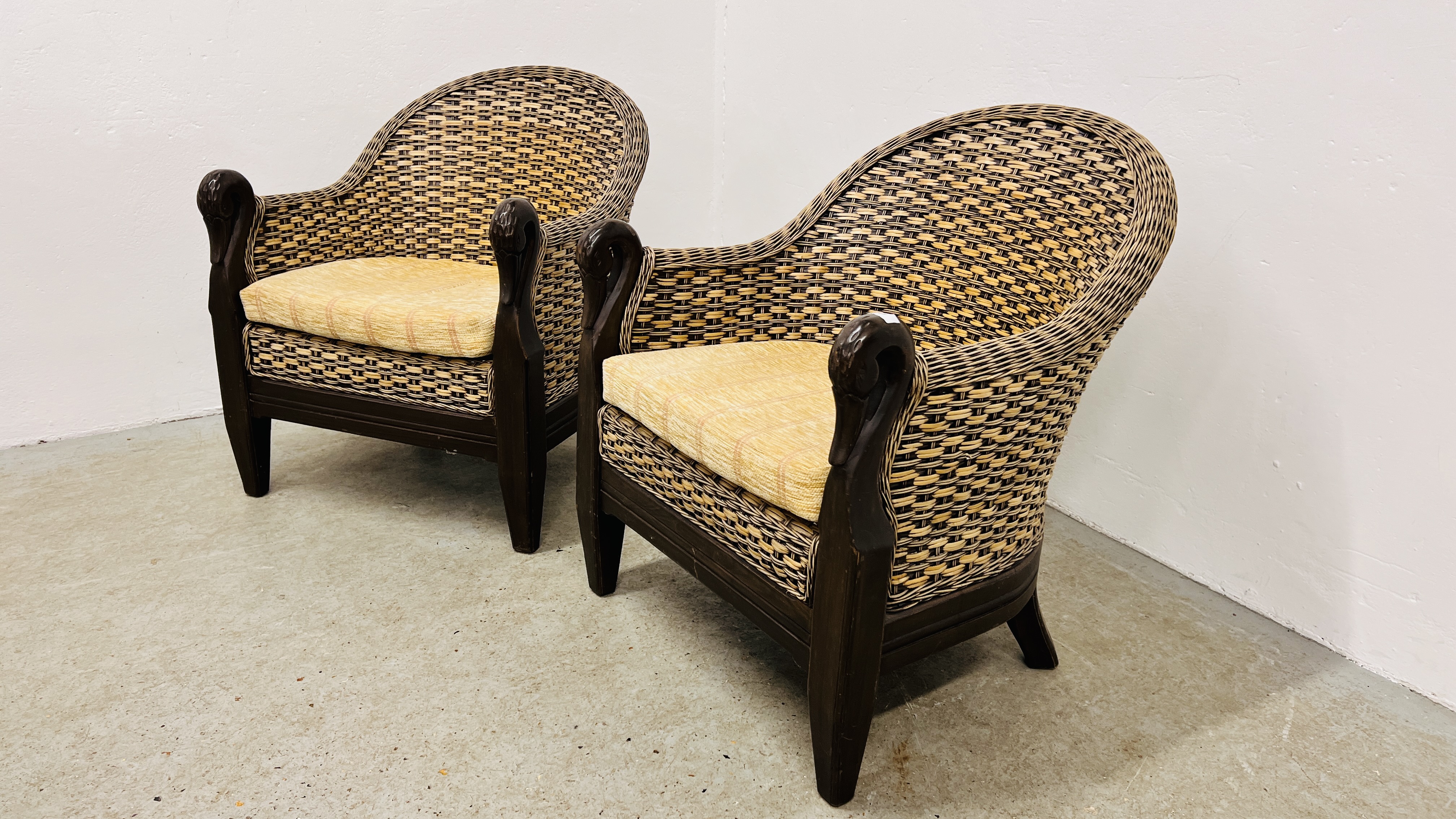 A PAIR OF WOVEN WICKER CONSERVATORY CHAIRS, THE SCROLLED ARMS WITH CARVED SWAN DETAIL,