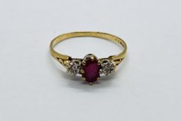 A 9CT GOLD RING SET WITH A CENTRAL OVAL RUBY AND A SMALL DIAMOND EITHER SIDE.