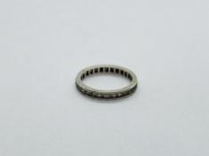 A WHITE METAL ETERNITY RING SET WITH CLEAR STONES.