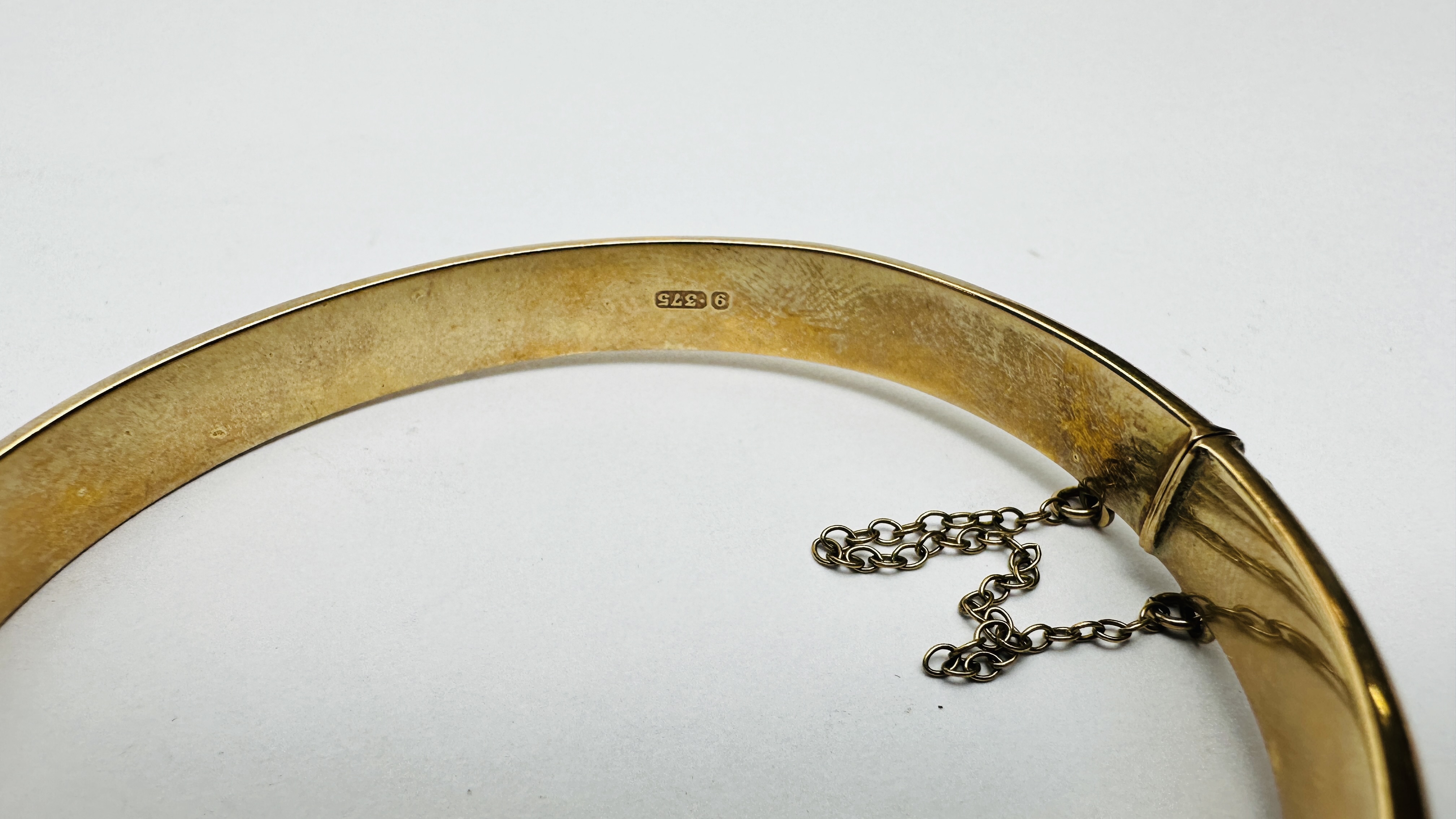 A 9CT GOLD HINGED BANGLE WITH SAFETY CHAIN AND CHASED DECORATION. - Image 3 of 6