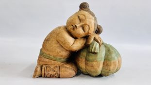 A CARVED WOOD SCULPTURE OF A GOOD LUCK CHILD SLEEPING ON A MELON, W 33CM X H 30CM.