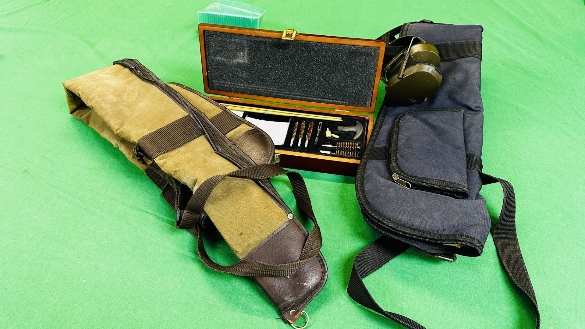 TWO CANVAS GUN SLIPS, BISLEY EAR DEFENDERS + CASED MULTI BORE CLEANING KIT.