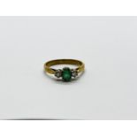 A 9CT GOLD RING SET WITH A CENTRAL GREEN STONE AND A DIAMOND EITHER SIDE.