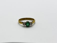 A 9CT GOLD RING SET WITH A CENTRAL GREEN STONE AND A DIAMOND EITHER SIDE.