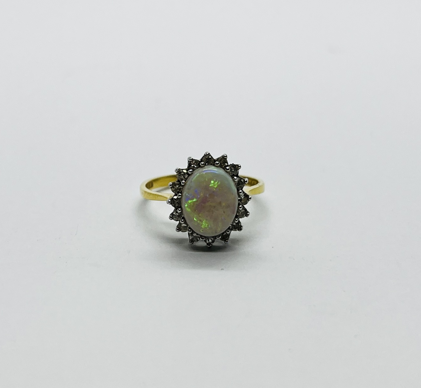 AN 18CT GOLD RING SET WITH A CENTRAL OVAL OPAL SURROUNDED BY DIAMONDS.