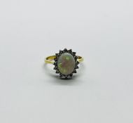 AN 18CT GOLD RING SET WITH A CENTRAL OVAL OPAL SURROUNDED BY DIAMONDS.