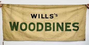 A VINTAGE CANVAS ADVERTISING BANNER TITLED "WILL'S WOODBINES" L 190CM X H 85CM.