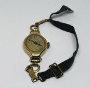 A VINTAGE LADIES WRIST WATCH ON MATERIAL STRAP CASE MARKED 14K.