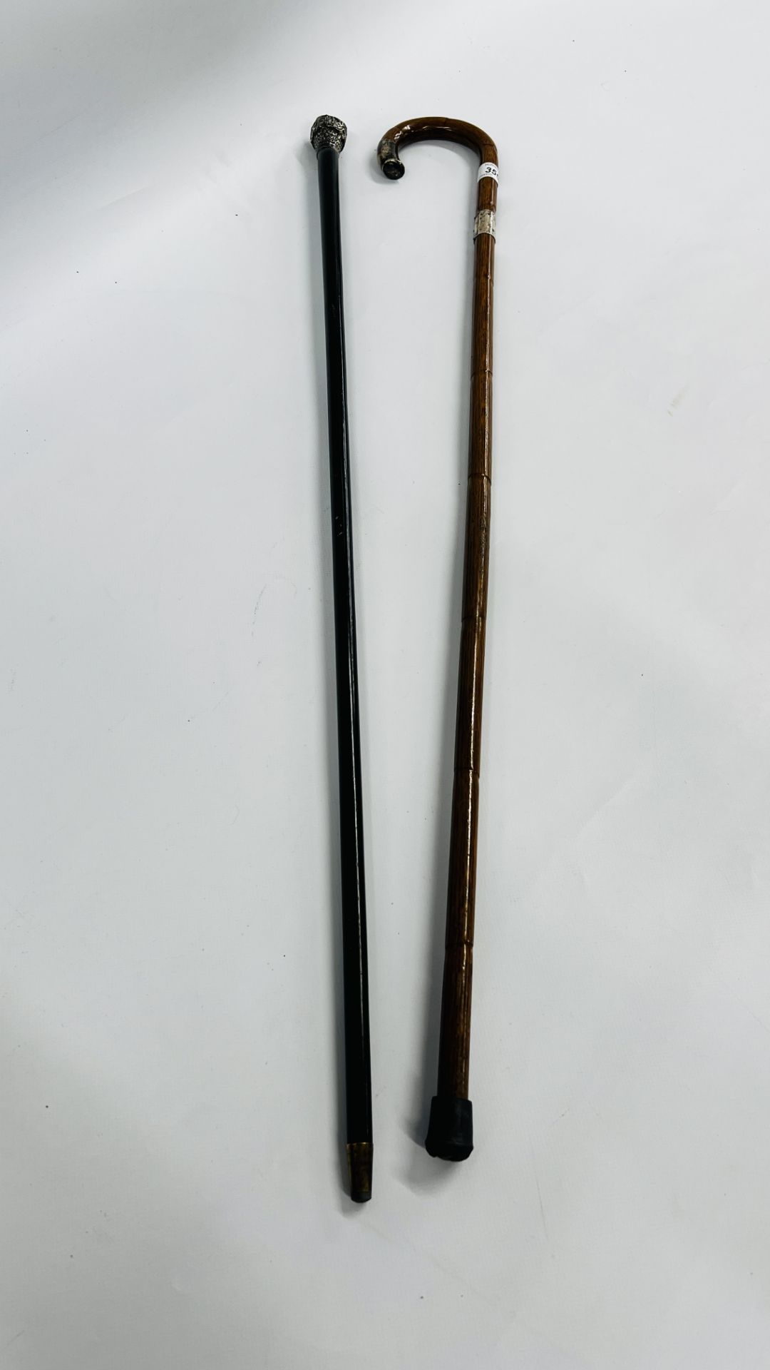 AN EBONY WALKING CANE WITH SILVER TOP A/F AND ONE FURTHER WALKING CANE WITH SILVER TOP AND BAND