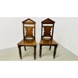 A PAIR OF SOLID OAK EDWARDIAN PANEL BACK HALL CHAIRS WITH PEDIMENTED BACKS A/F.