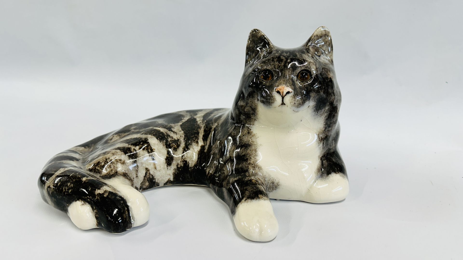 A HANDCRAFTED WINSTANLEY NO. 7 LAYING CAT FIGURE - HEIGHT 19CM, LENGTH 33CM.