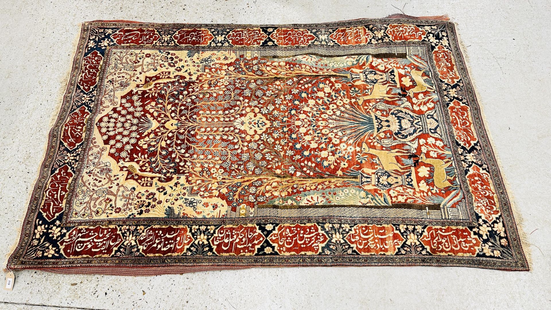 A PERSIAN DESIGN RUG DECORATED WITH SPRAYS OF FLOWERS AND DEER AND ARABIC INSCRIPTIONS,